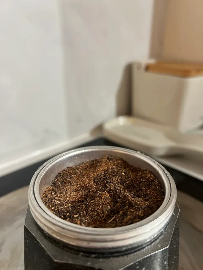 Moka pot filter basket filled with ground Karobe, ready to brew a caffeine-free espresso alternative.